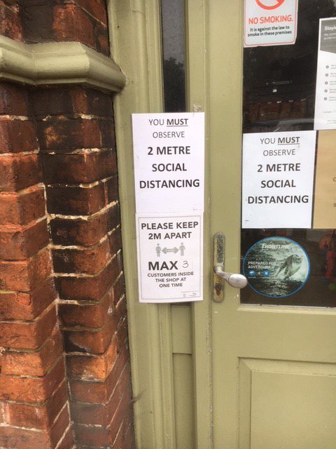 A 2m social distancing poster on a shop door