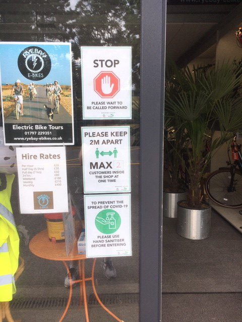 3 Covid-19 posts outside a shop asking people to wear a mask, stay 2m apart and to use hand sanitiser